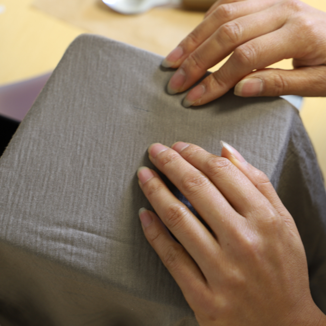 Hands checking a repaired seam on a grey LOOW merino garment