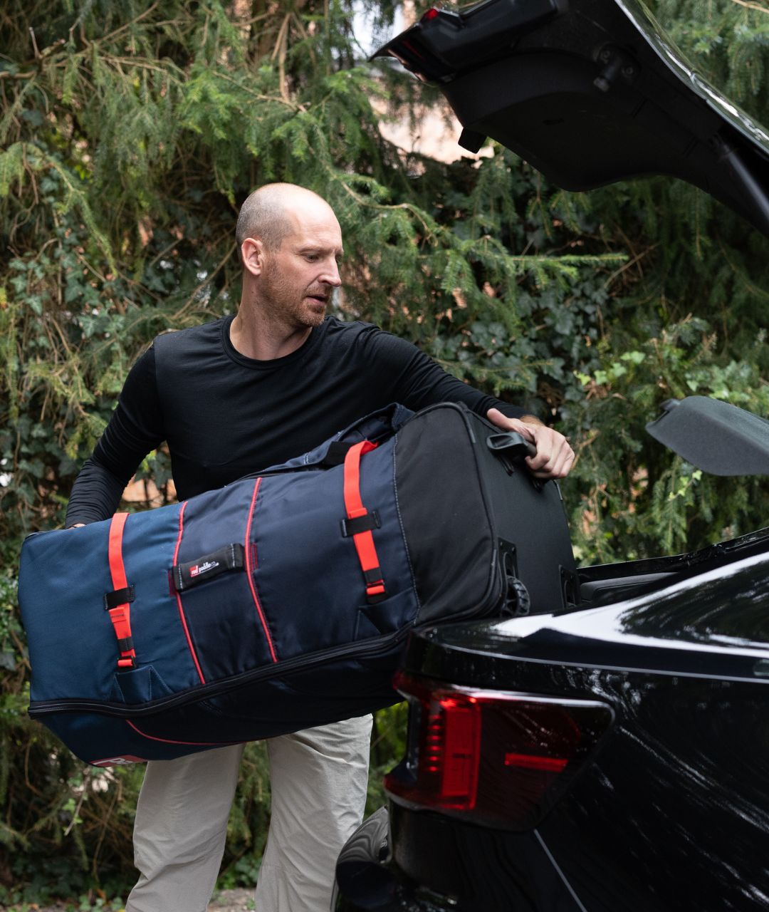 Anders Lorentzen loading a duffel bag into a car in a black LOOW merino long sleeve